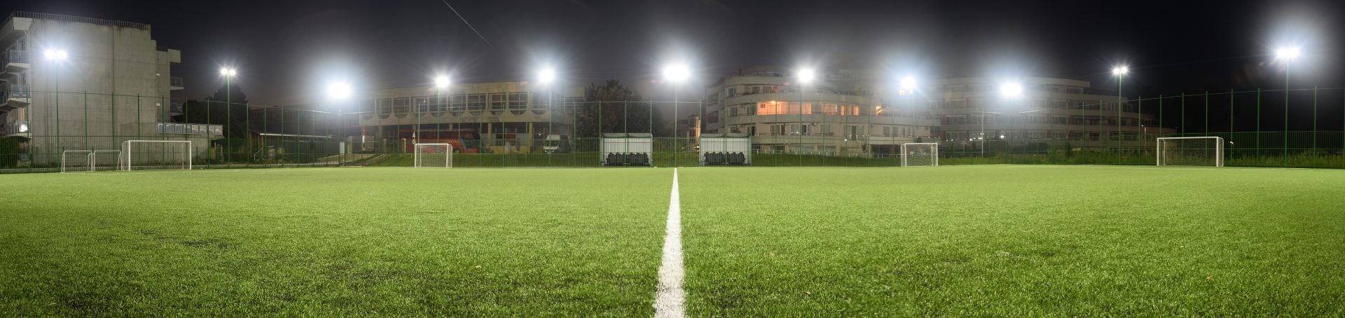 Night view of illuminated soccer field with center line and goals, prepared for evening training camp workouts