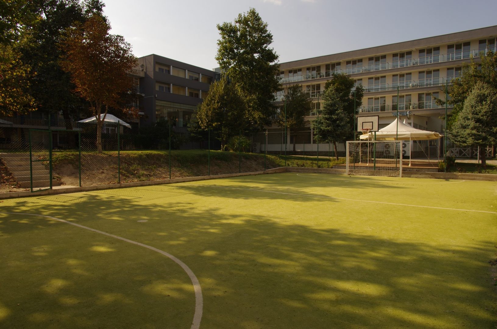 Small outdoor court with curved markings near residential buildings, used for warm-up practice sessions