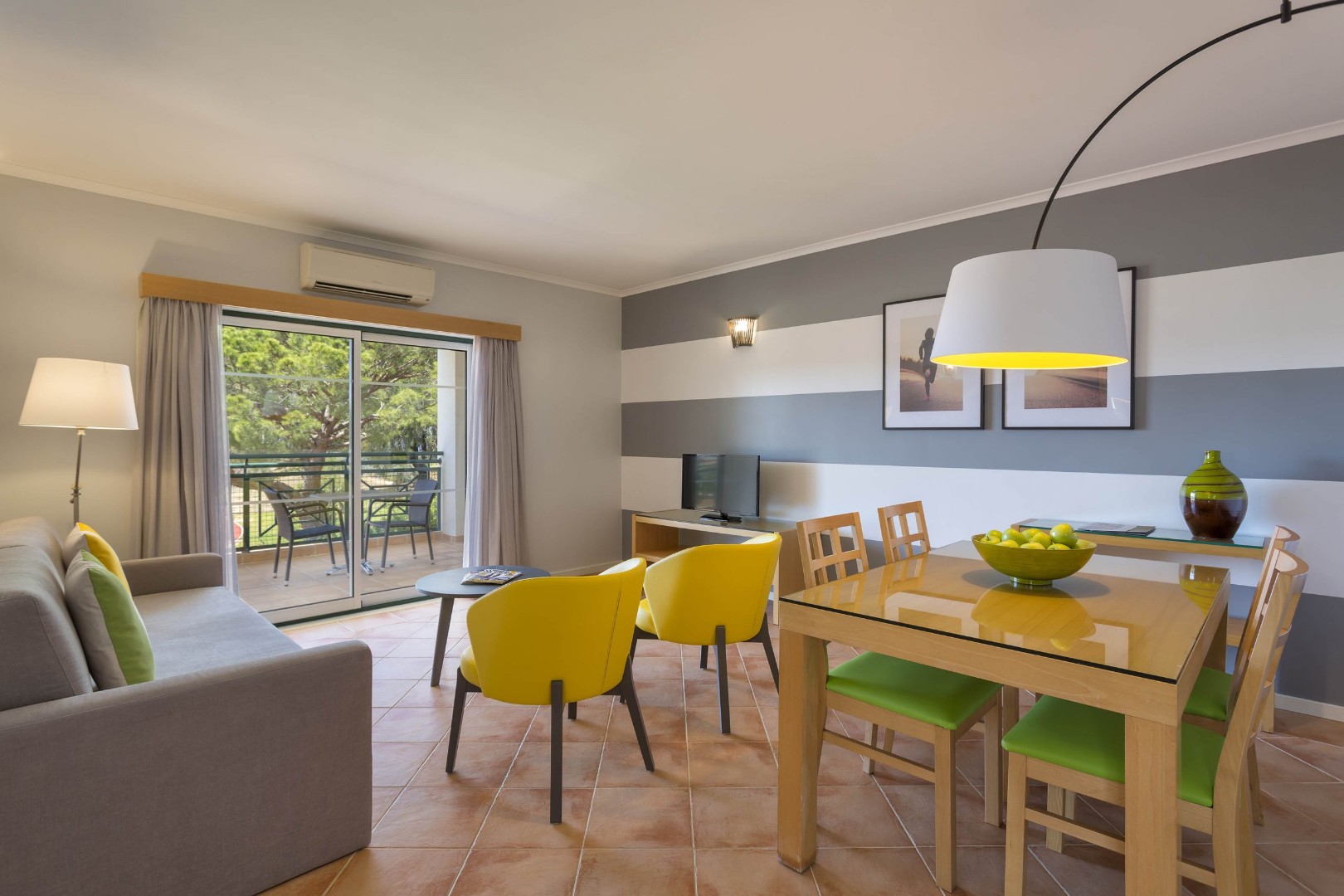 Espace salon et salle à manger d'appartement avec canapé, table et coin balcon.