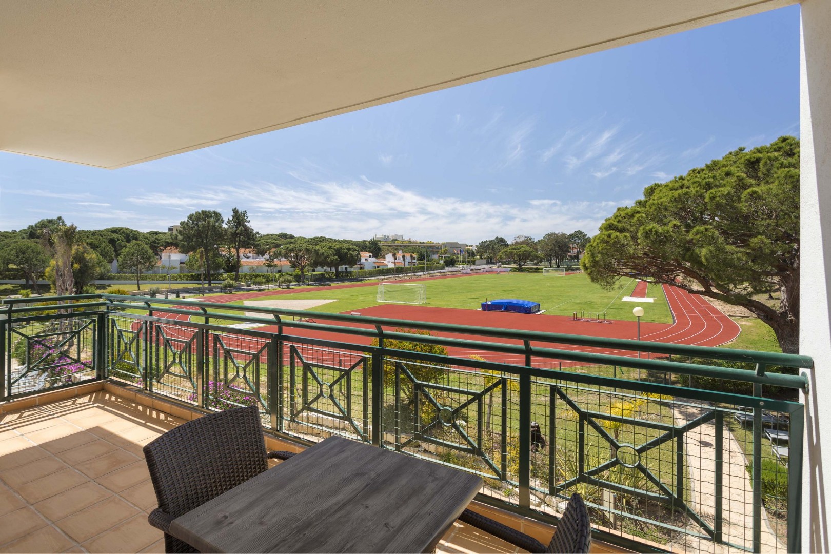 Balcon avec table surplombant une piste d'athlétisme et un terrain en herbe.