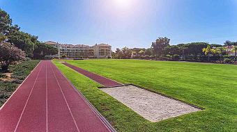 Leichtathletikbahn mit Weitsprunggrube neben dem Rasen-Infield.