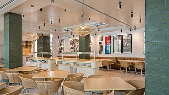 Innenrestaurant mit Sitzplätzen, Buffetstation und sportlichen Wandbildern.