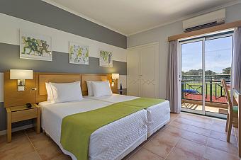 Gästezimmer mit zwei Betten, Balkon und Blick Richtung Sportfeld.