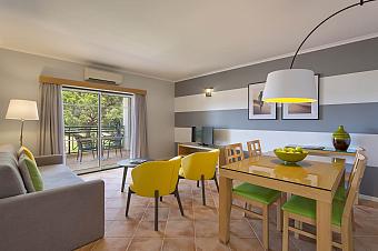 Wohn- und Essbereich im Apartment mit Sofa, Tisch und Balkonbestuhlung.