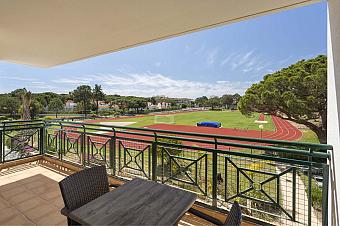 Balkon mit Tisch und Blick auf Laufbahn und Rasenfeld.