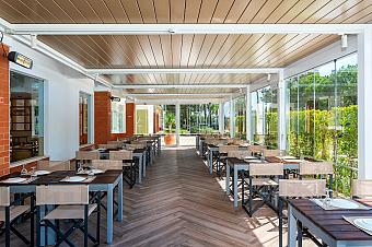 Überdachte Restaurantterrasse mit gedeckten Tischen und Glaswänden.