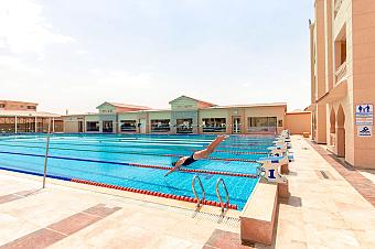 Athlete diving into Olympic-size pool from starting block in practice