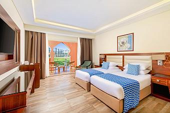 Hotel room with two single beds, balcony access, and blue decor accents