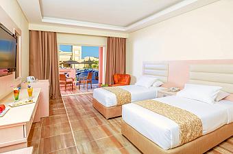 Guest room with twin beds, TV, and balcony view with outdoor seating