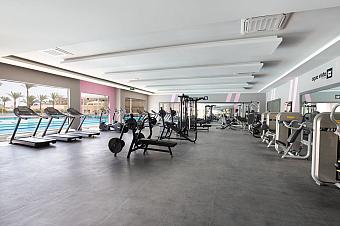 Spacious gym with treadmills, weight machines, and poolside view