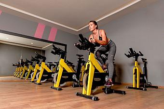 Woman training on yellow indoor spin bike in mirrored cycling studio