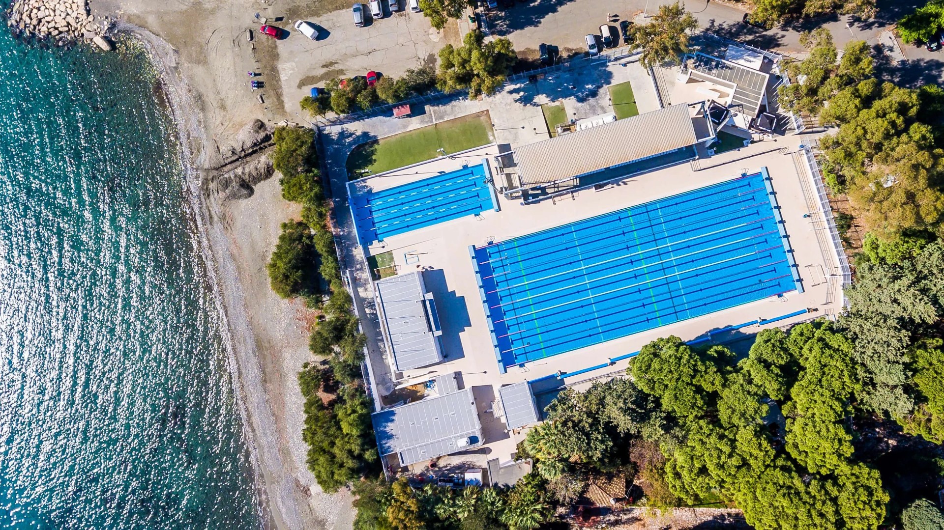 Draufsicht auf blaue Schwimmbecken neben dem Strand, ideal für Schwimmtrainingslager