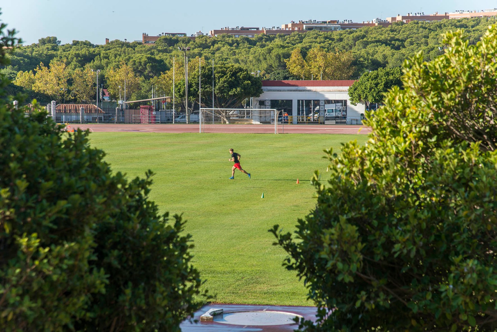 Athlet bei Laufdrills auf dem Raseninnenfeld neben der Laufbahn.