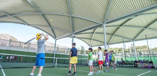 Überdachter Tennisplatz mit Spielern in einer Gruppen-Trainingseinheit.