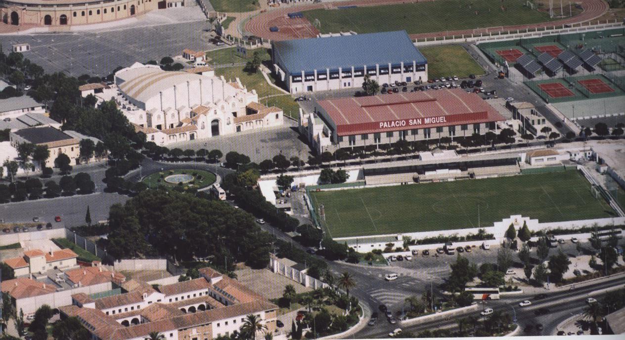 Luftaufnahme eines Sportkomplexes mit Fußballplatz, Sporthalle und Tennisplätzen.