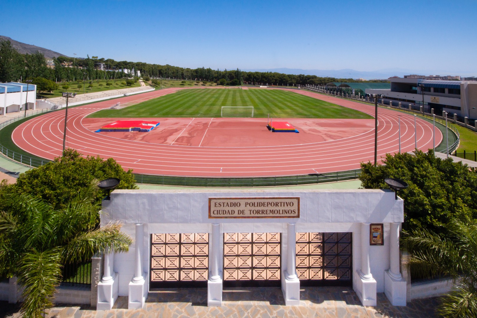 Eingang eines Leichtathletikstadions, dahinter die Laufbahn.