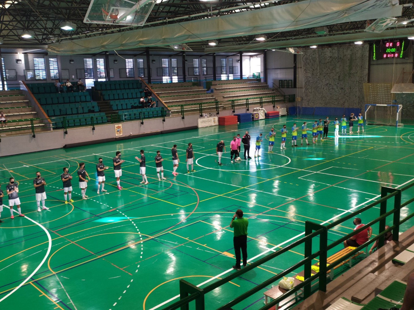 Indoor-Spielfeld mit aufgestellten Teams und Zuschauertribüne.