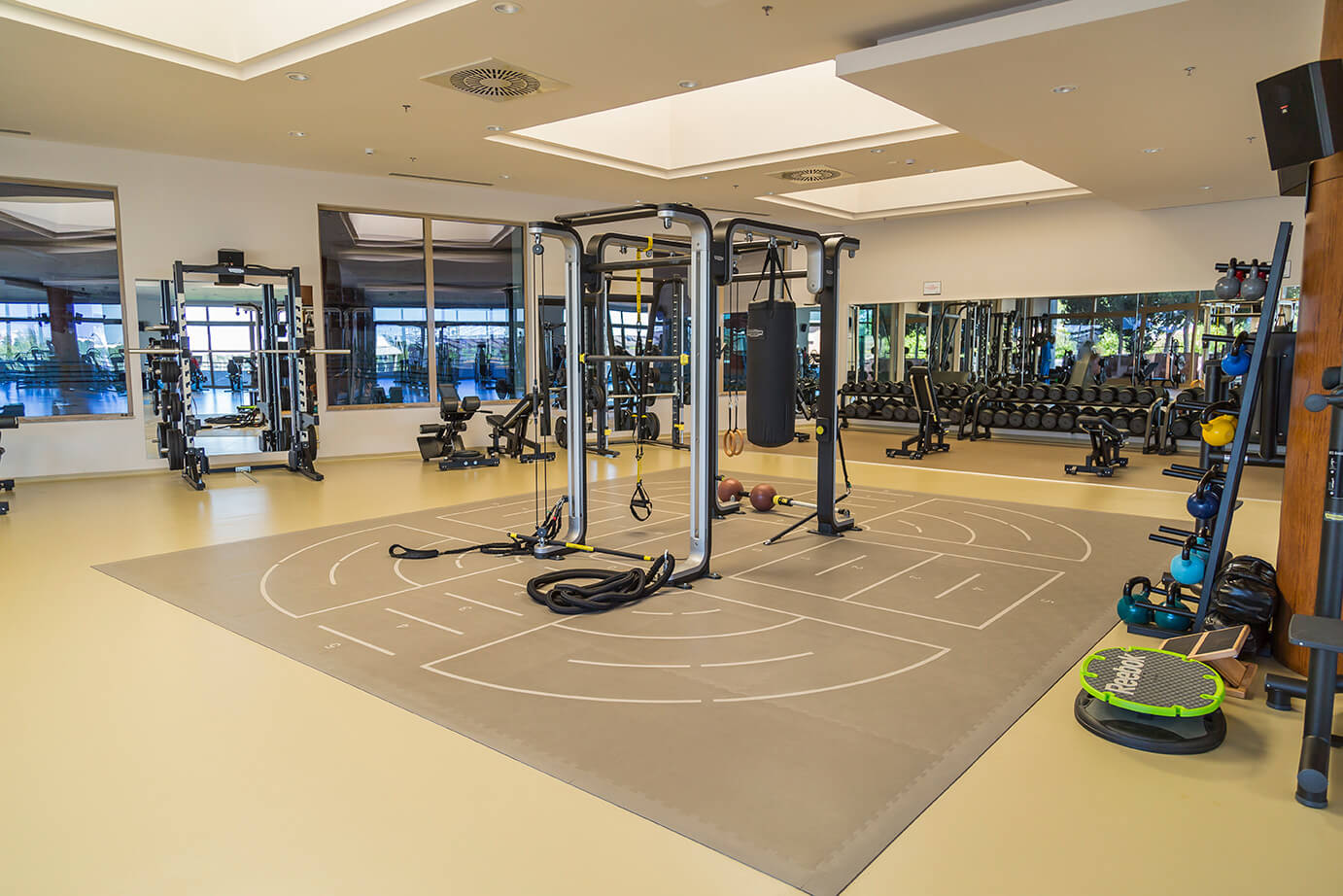 Großzügiges Functional-Training-Studio mit Multistation-Rig, Schlingentrainern und Boxsack, ergänzt durch Freihanteln und Kettlebells. Die offene Fläche bietet viel Platz für Mobility, Dehnen und Zirkeltraining.