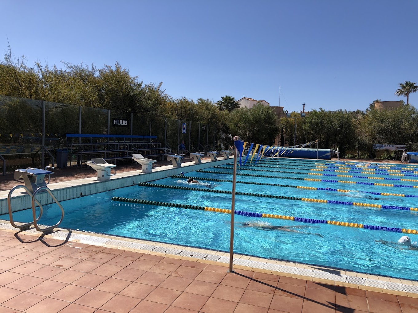 Außen-Trainingsbecken mit Schwimmern, Leinen und kleiner Zuschauertribüne.