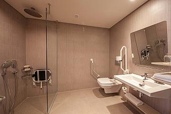 Bright, spacious suite living area with lounge seating, dining table and large windows for natural light. A comfortable layout offers room to relax, work or meet as a small group.