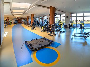 Strength and conditioning room with a broad range of resistance machines and open training space. Marked flooring and performance equipment support speed, power and athletic development sessions.