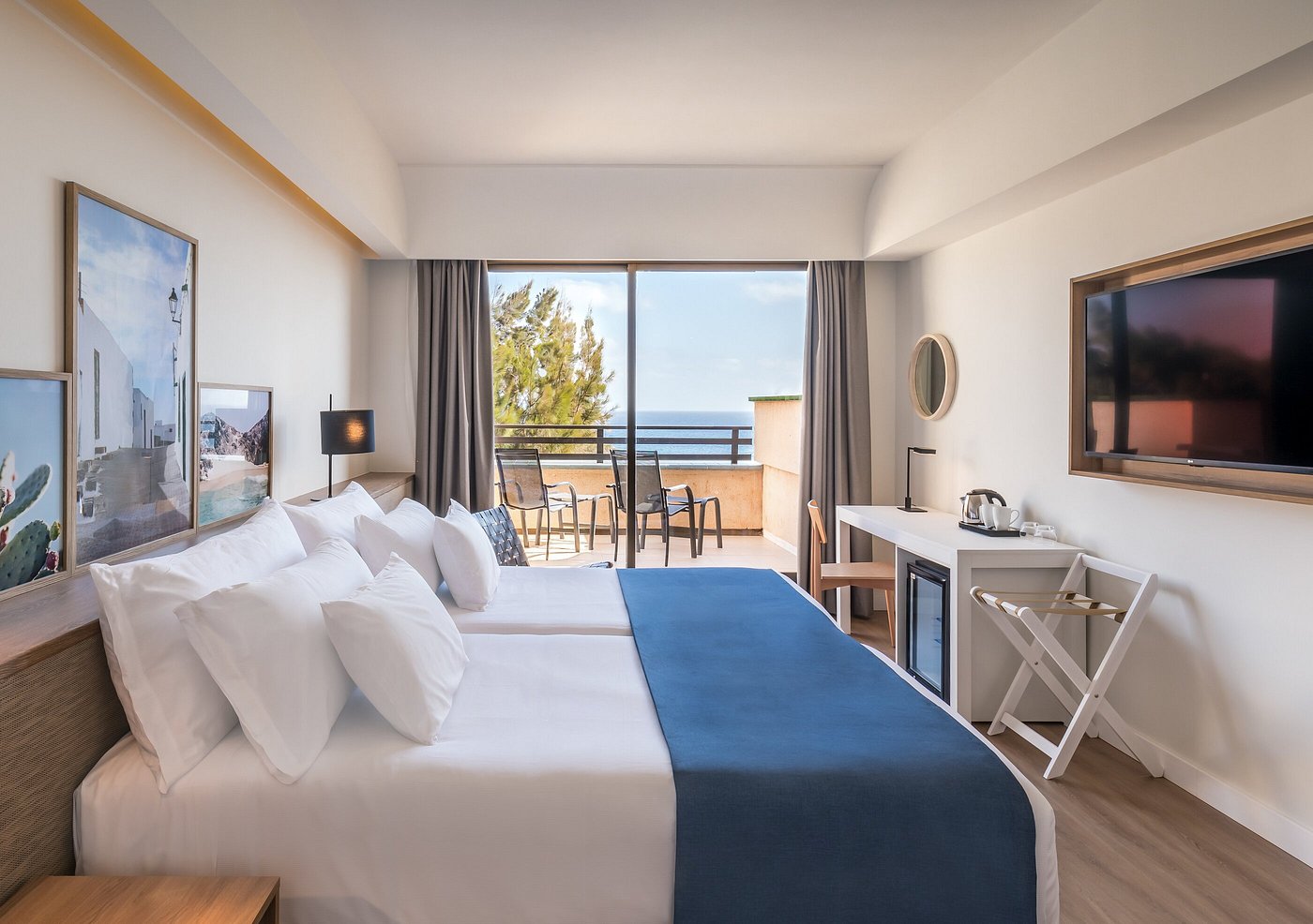 Chambre moderne avec lit double, bureau, télévision et balcon avec vue sur la mer.