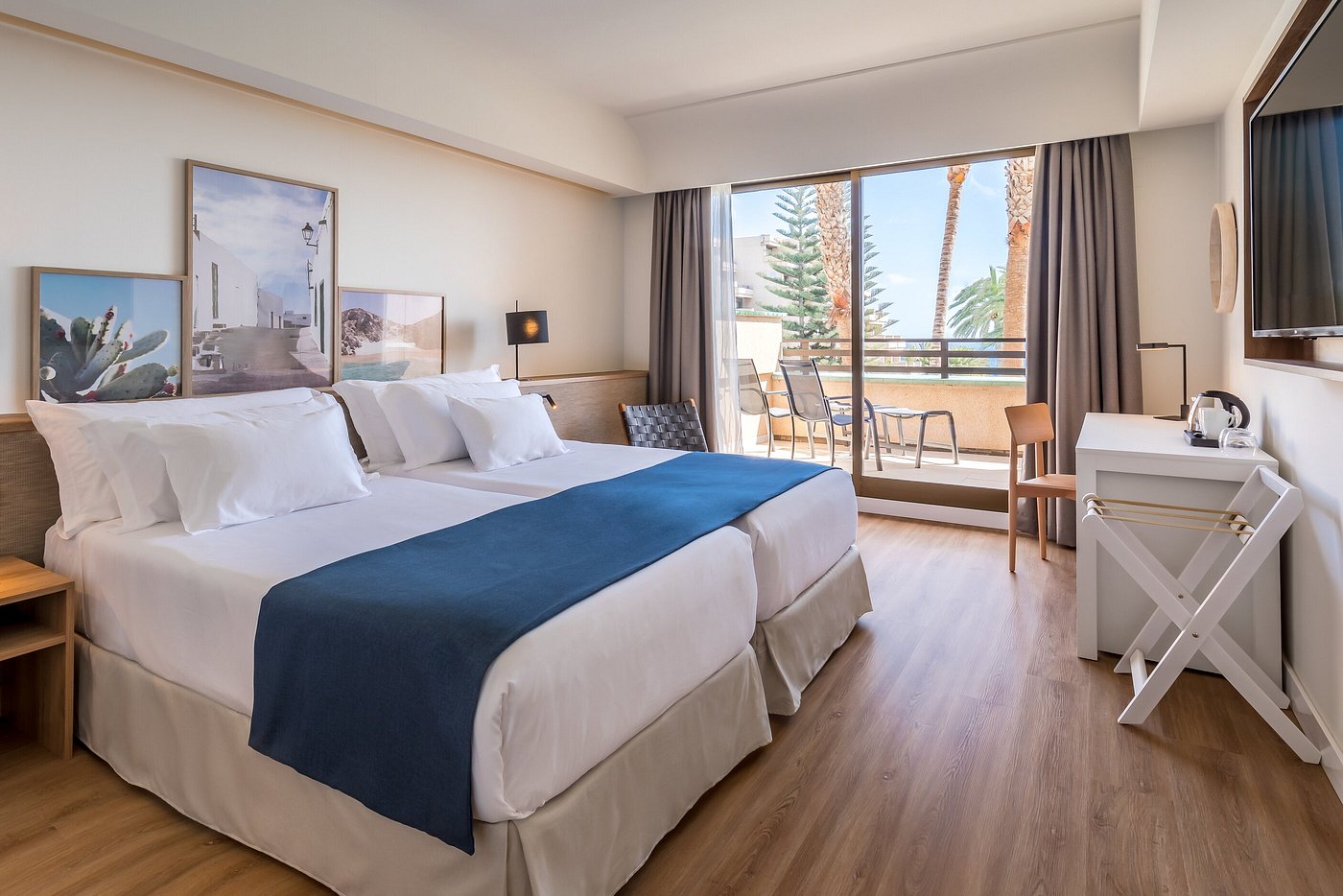 Chambre twin contemporaine avec coin salon sur balcon, parquet en bois et grandes portes coulissantes vitrées.