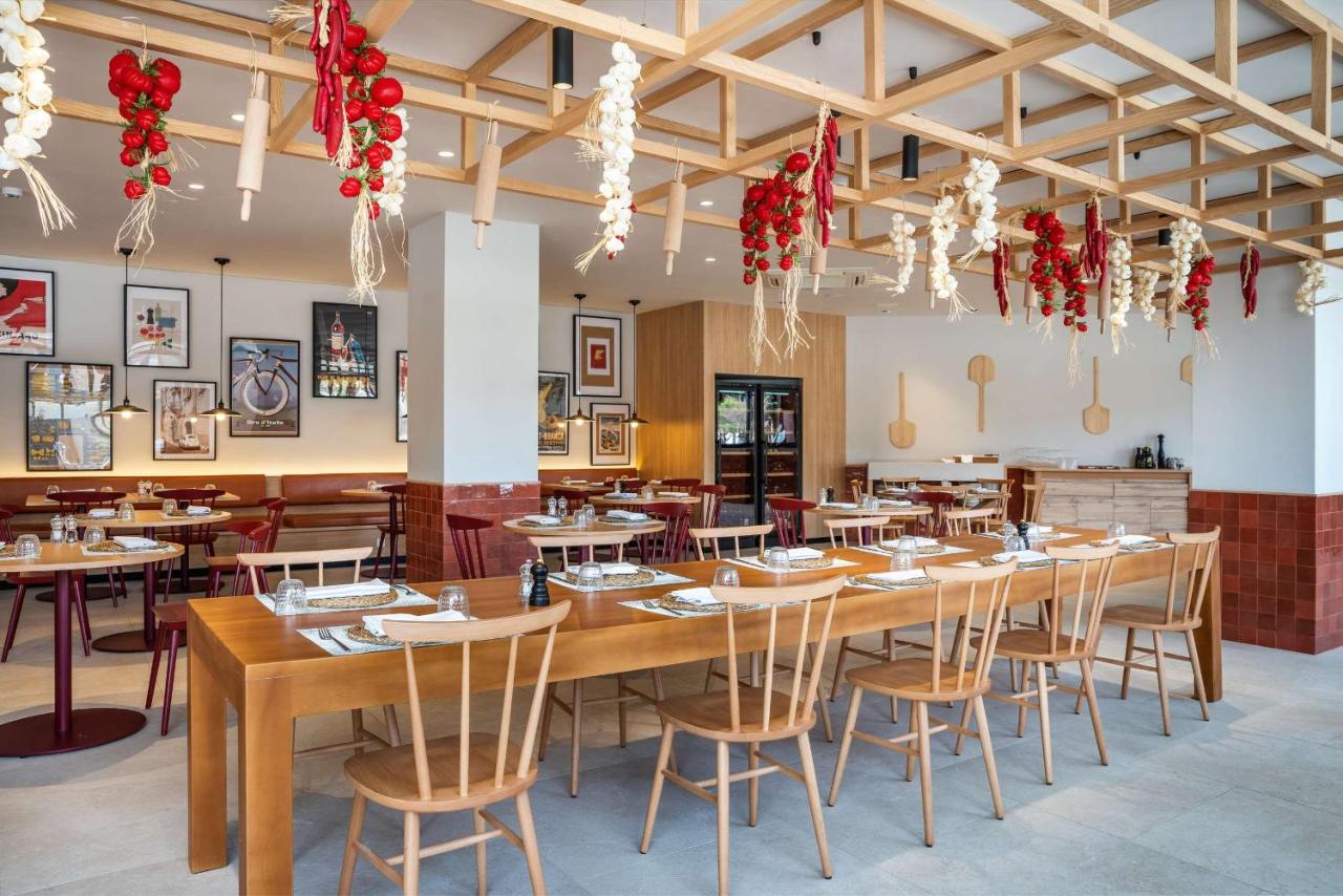 Salle de restaurant avec tables partagées, décor en bois et ail et tomates suspendus.
