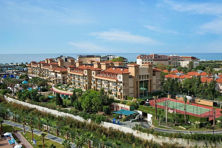Panoramic view of the resort buildings with landscaped grounds and tennis courts.