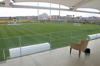 Covered terrace with a chair overlooking a football pitch set up for drills and balls.
