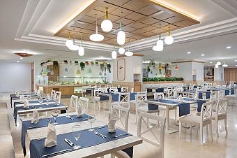 Bright restaurant dining hall with buffet counters and set tables.