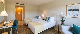 Twin guest room with desk, armchair and two single beds.