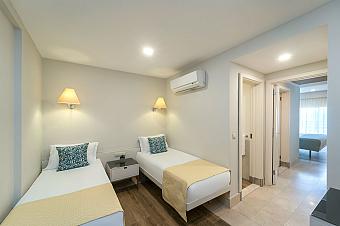 Suite with two single beds and a hallway to a separate bedroom.