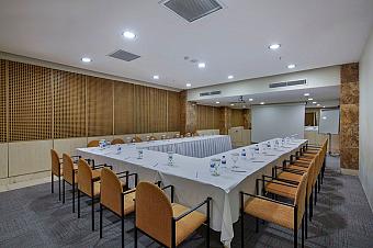 Conference room with U-shaped tables, water bottles, projector screen and flip chart.
