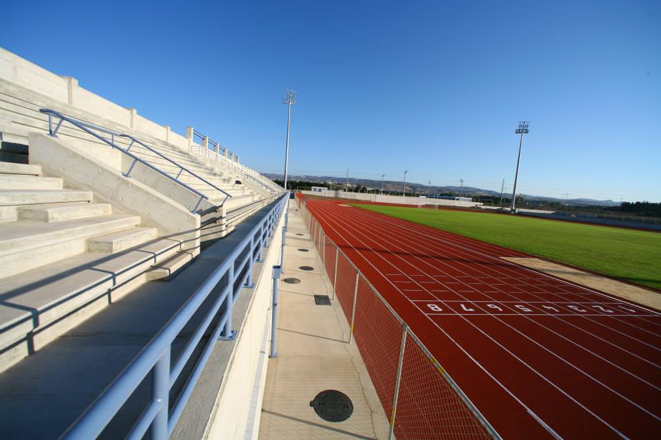 View from the stands over a red running track and grass infield.