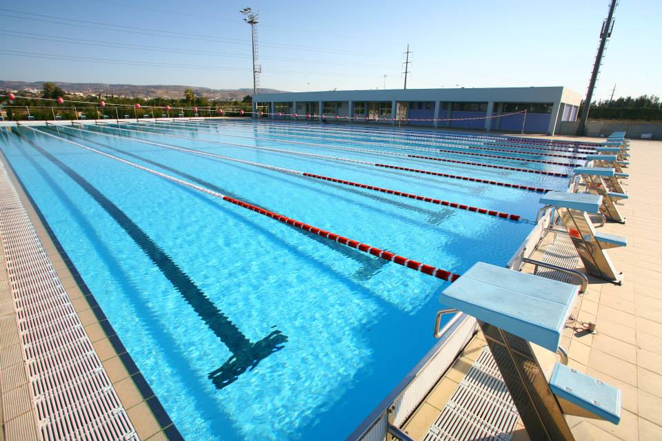 Outdoor lap pool with starting blocks and a poolside building.
