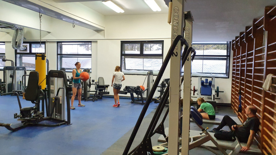 Intérieur de salle de sport avec athlètes utilisant des machines et espaliers pendant les entraînements structurés en stage