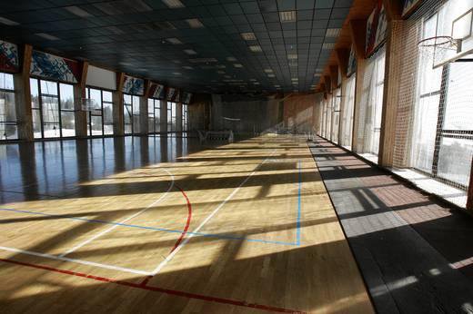 Grande salle de sport intérieure avec parquet et lignes de terrain, préparée pour les séances d'entraînement en équipe