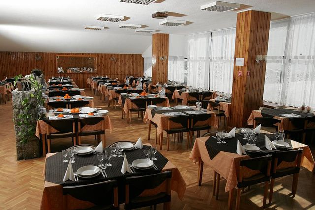 Salle à manger avec tables dressées, assiettes et couverts préparés pour les repas d'équipe pendant le stage d'entraînement