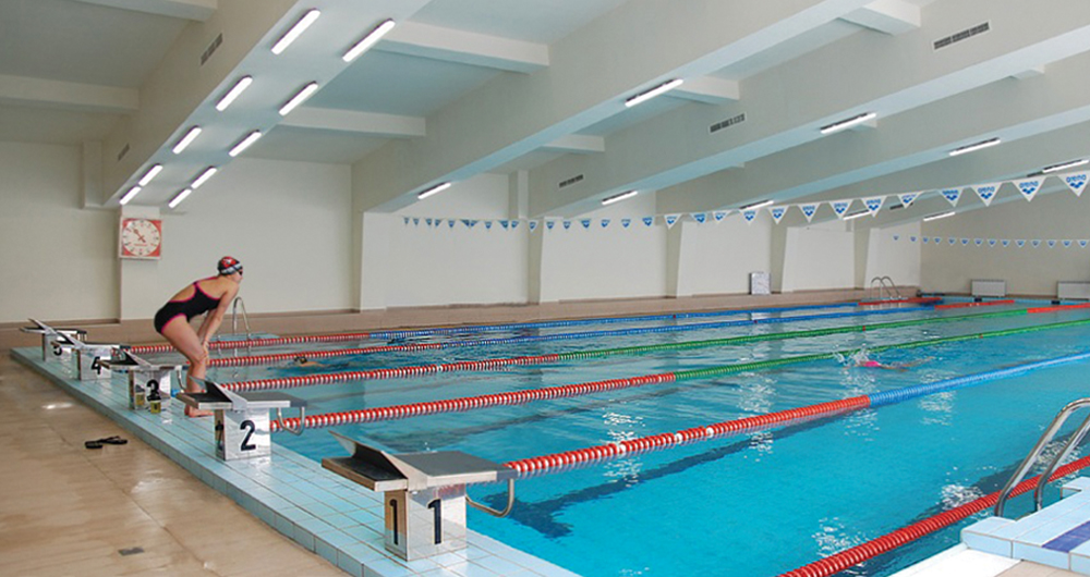 Bassin de natation intérieur avec lignes d'eau et plots de départ, séance d'entraînement des athlètes pendant le stage de natation