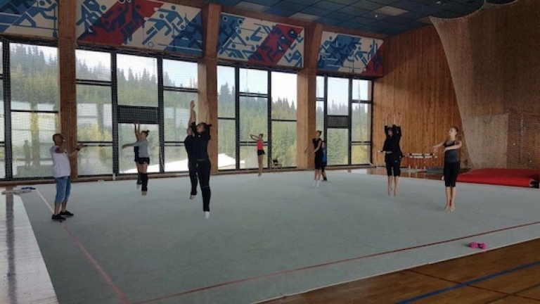 Athlètes effectuant des sauts sur un tapis de gymnastique à l'intérieur d'une salle de sport pendant une séance de stage