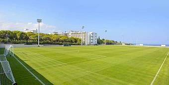 Outdoor football training field with goalposts, floodlights, and nearby resort building
