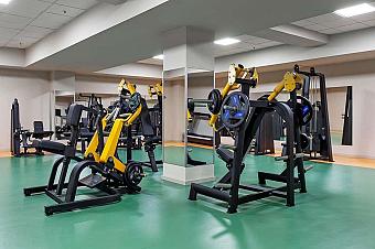 Fitness room with strength training machines and green flooring for athlete training