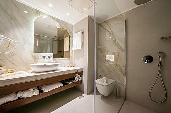 Modern bathroom with marble sink, glass shower, toilet, and vanity counter