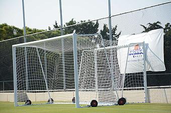 Portable football goals with nets on grass field near training camp