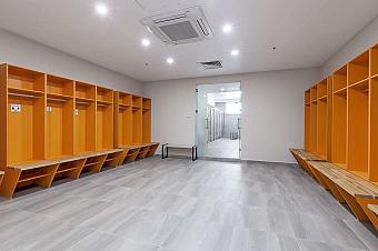 Locker room with orange cubbies, benches, and tiled floor for athletes