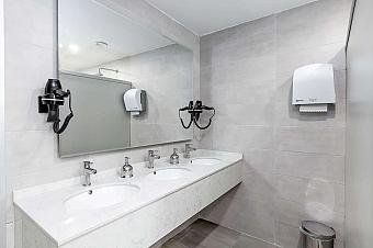 Bathroom with three sinks, wall mirror, hairdryer, and soap dispensers