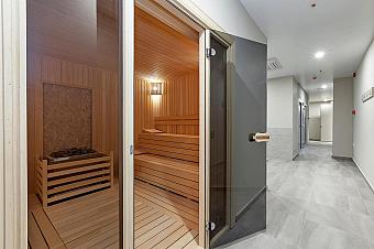 Wooden sauna room with tiered benches and heater stones, part of recovery facilities for athletes at a training camp