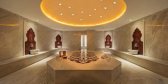 Large marble hammam with central stone platform and wash basins, recovery facility for athletes in training camp
