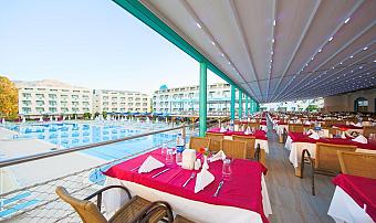 Poolside dining terrace under a canopy, with set tables facing the outdoor pool.